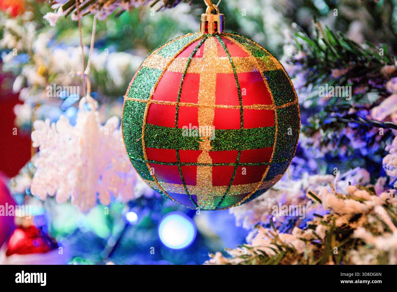 Un globo multicolore sull'albero di Natale con luci e ornamenti, sfondo natalizio Foto Stock