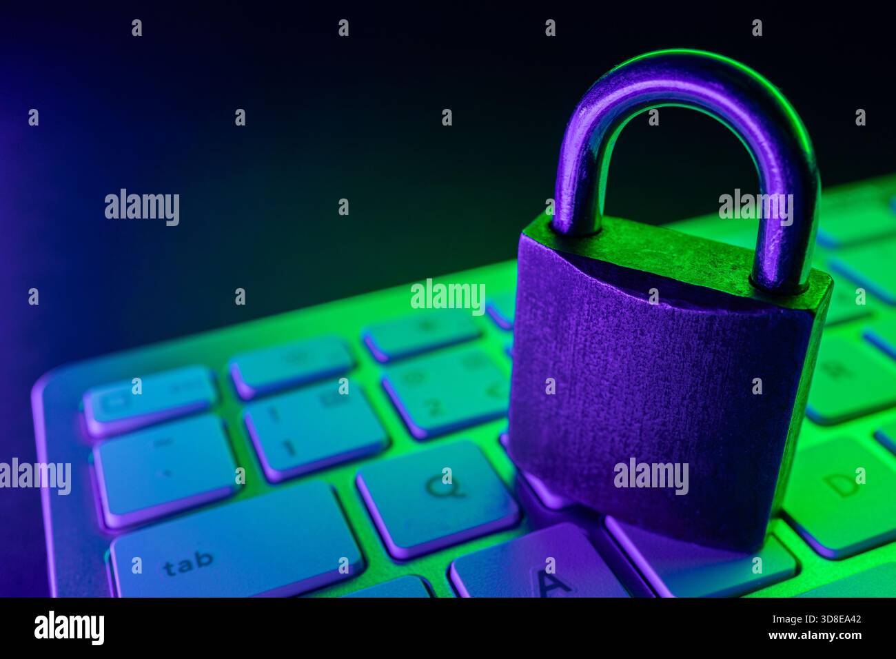 Un lucchetto si trova su una tastiera, simboleggiando la sicurezza informatica. L'illuminazione colorata sottolinea l'importanza della sicurezza di Internet nella protezione dei dati e della protezione dell'ambiente Foto Stock