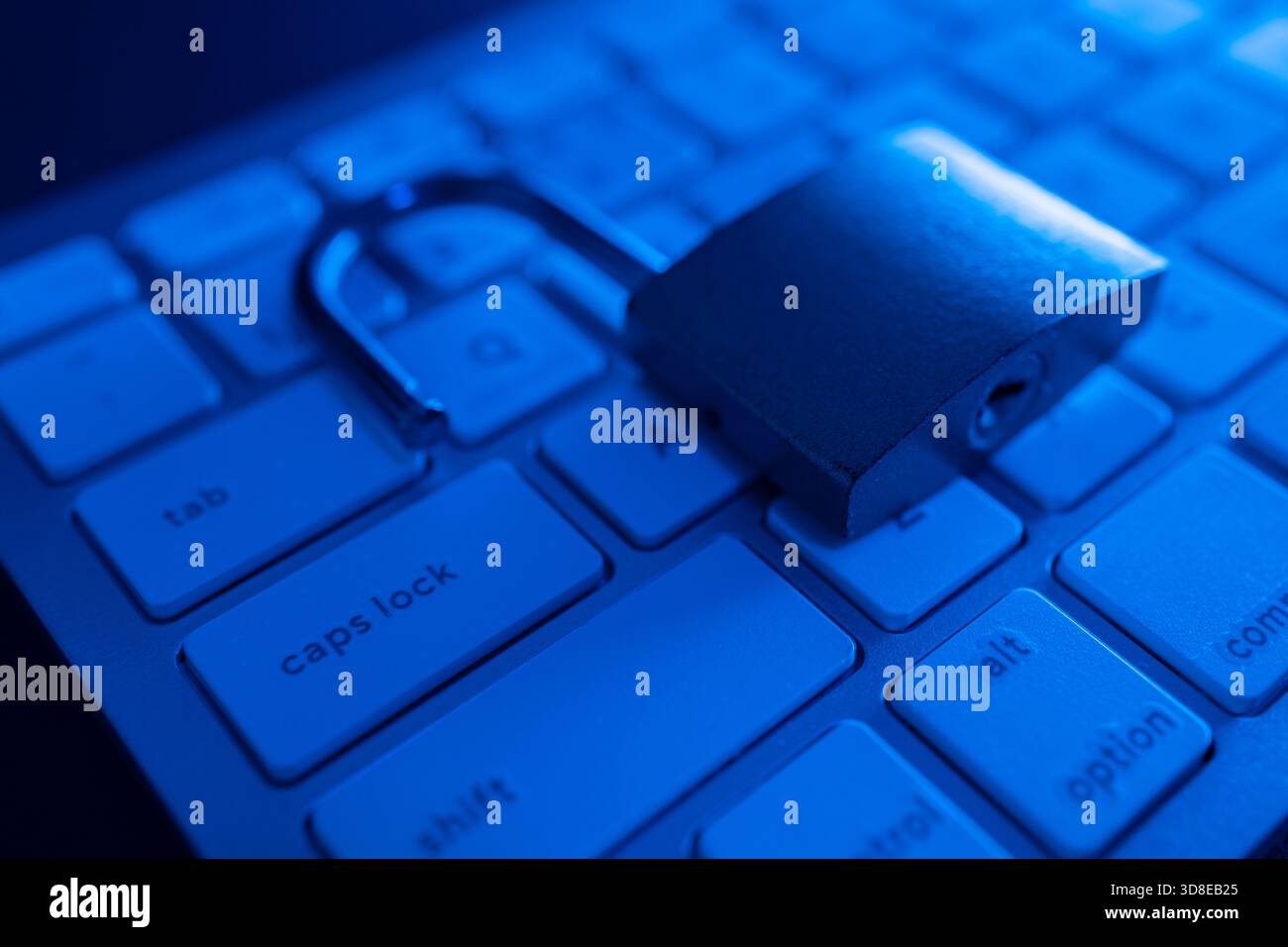 Un lucchetto metallico è aperto su una tastiera, a simboleggiare i problemi di sicurezza informatica. L'illuminazione soffusa aggiunge un tocco di atmosfera, sottolineando l'importanza dell'inte Foto Stock