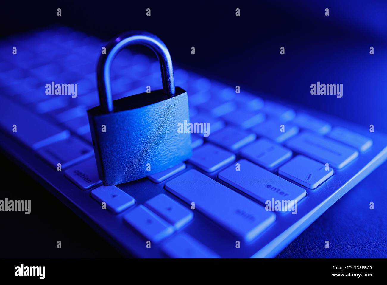Un lucchetto sicuro si trova sulla tastiera di un computer, simboleggiando l'importanza della sicurezza informatica e della sicurezza su Internet. L'illuminazione blu aggiunge un tocco moderno Foto Stock