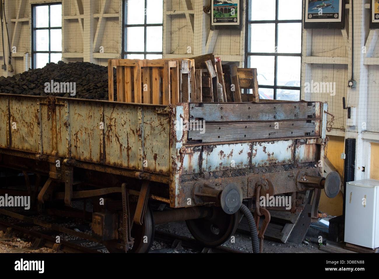 Storico vagone industriale carico di materiale all'interno di una ferrovia storica o di un edificio industriale, che illustra la storia dei trasporti e l'industria del lavoro Foto Stock