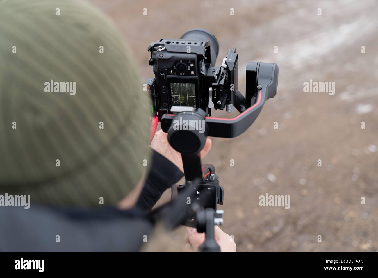 Configurazione professionale delle riprese con una fotocamera mirrorless su uno stabilizzatore cardanico tenuto da un operatore per scattare foto stabilizzate in condizioni esterne fredde Foto Stock