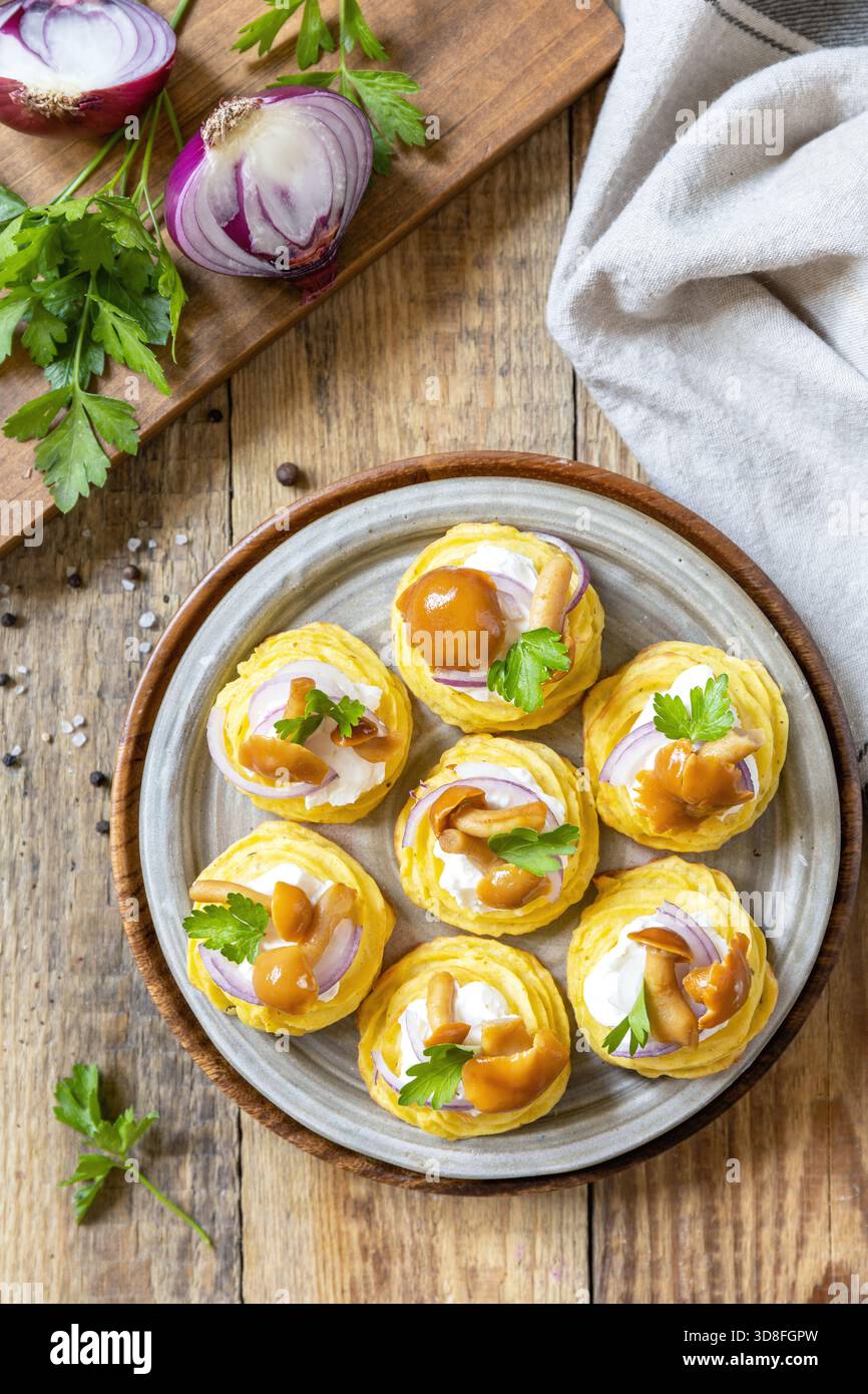 Tartine di patate ripiene di formaggio fresco e funghi marinati su uno sfondo rustico. Sfondo piatto della vista superiore. . Foto Stock