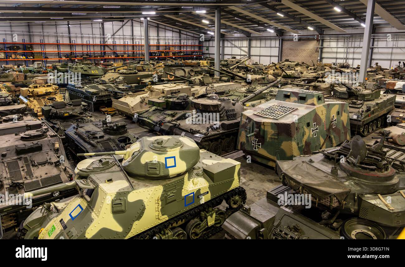 Collezione di carri armati militari storici e veicoli corazzati esposti all'interno di un grande deposito museale al coperto Foto Stock