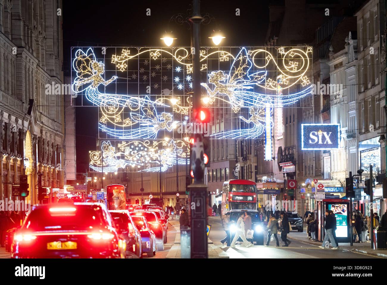 Le luci natalizie adornano lo Strand, Londra, mentre gli acquirenti e il traffico navigano nel panorama delle festività. Foto Stock