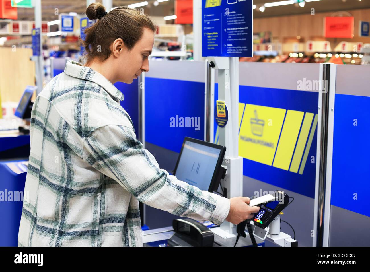 Un uomo usa uno smartphone per pagare in un moderno terminale self-service in un negozio di alimentari o in un supermercato. Foto di alta qualità Foto Stock