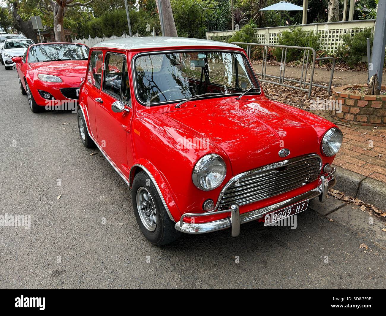 Mini Cooper S rossa classica parcheggiata in strada con una Mazda MX-5 rossa parcheggiata dietro, su targhe australiane. Foto Stock