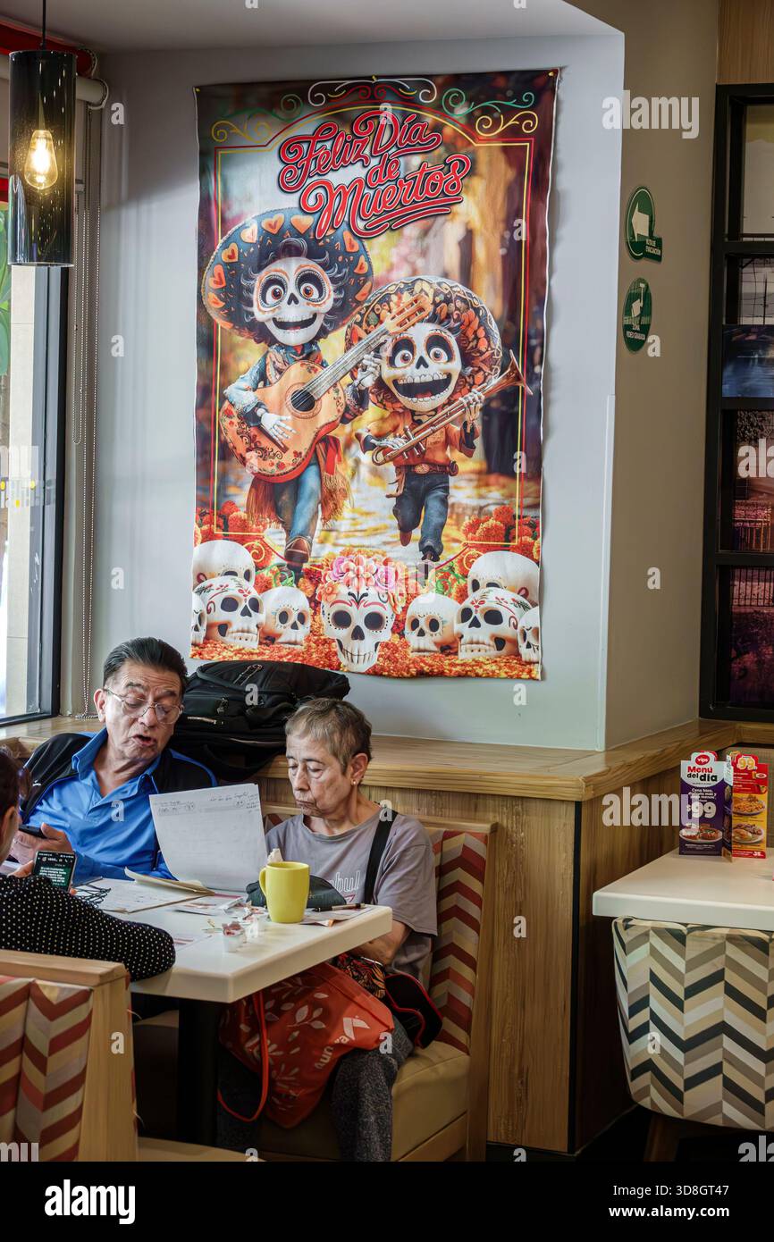 Città del Messico, Messico, Benito Juarez, ristorante Vips Universidad, poster dia de Muertos, personaggi colorati del cranio, coppia di anziani seduti, senio adulto Foto Stock