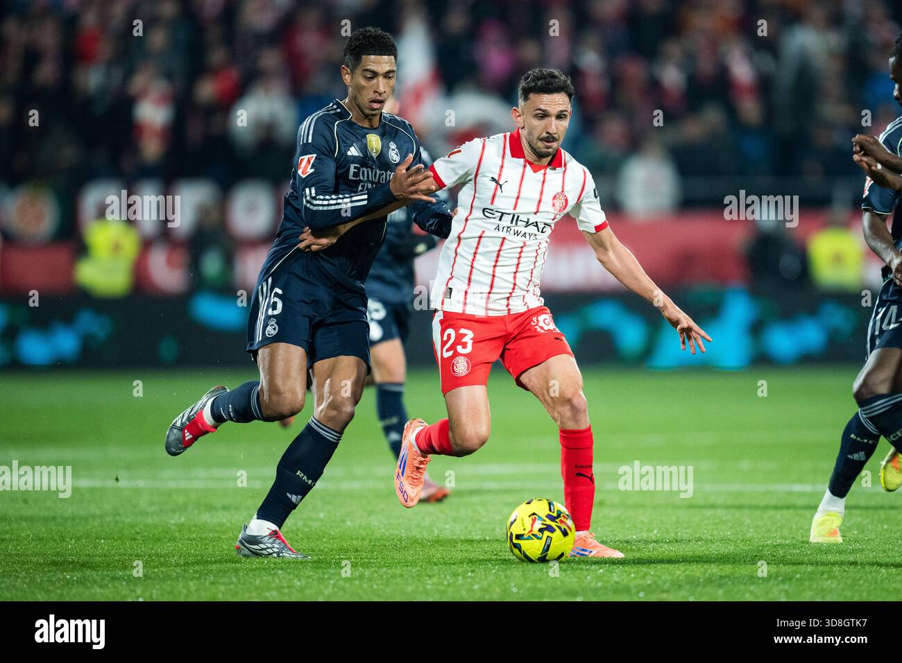 Girona, Spagna. 30 novembre 2025. Jude Bellingham (L) del Real Madrid CF sfida con Ivan Martin del Girona FC durante la partita di calcio della Liga tra il Girona FC e il Real Madrid CF allo Stadio Montilivi, Girona, Spagna, il 30 novembre 2025. Crediti: Joan Gosa/Xinhua/Alamy Live News Foto Stock