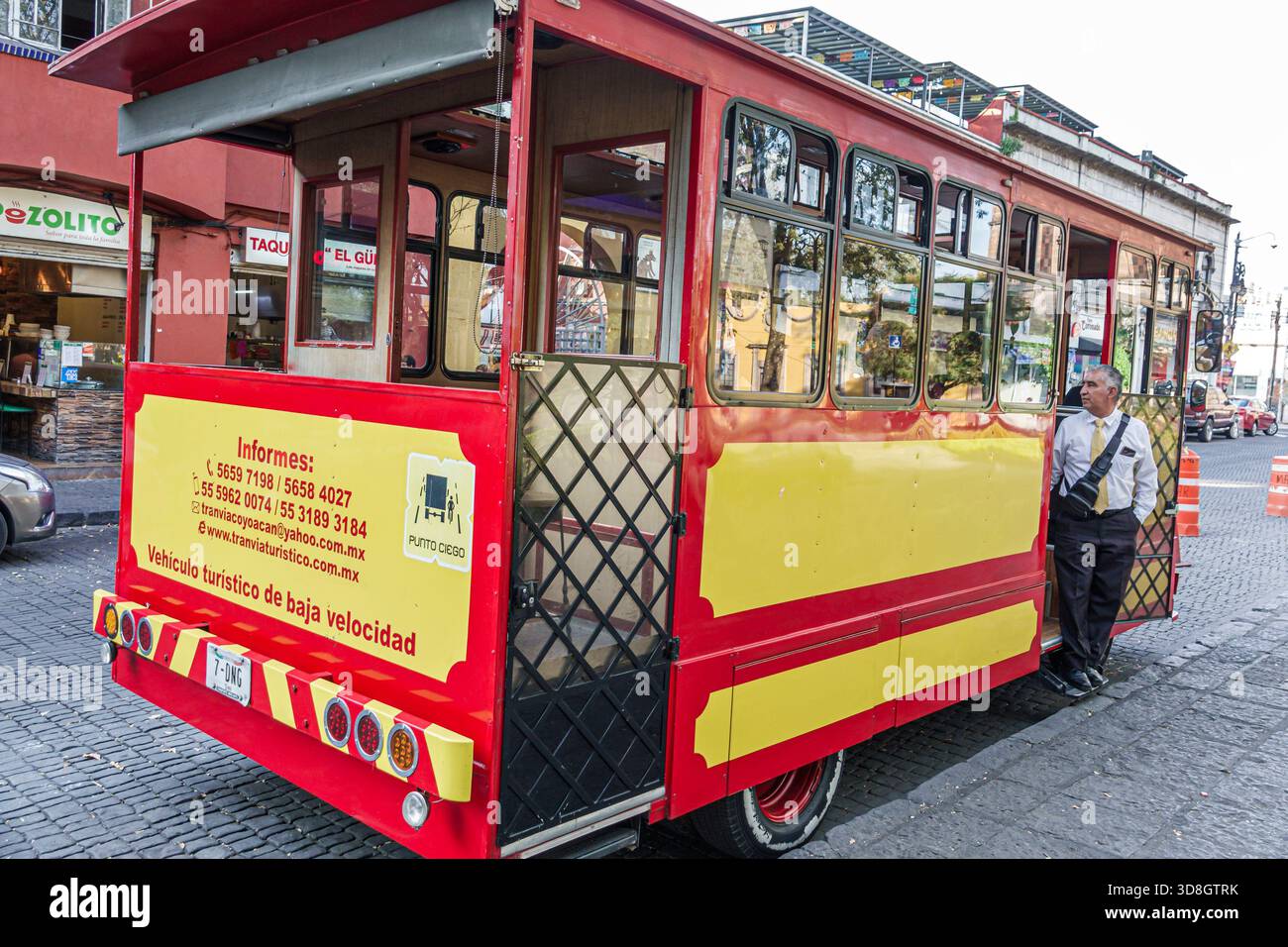 Città del Messico, Messico, Coyoacan, tram turistico giallo rosso del Carmen 004, autista adulto, ispanico in piedi accanto ai passeggeri a porta aperta che si preparano a salire a bordo Foto Stock