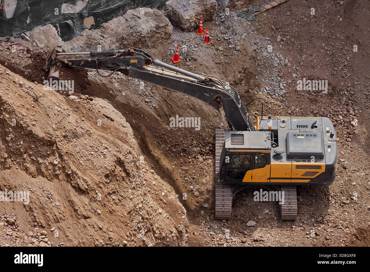 Scavo da un escavatore in un cantiere edile, spostamento di terreno e rocce durante lavori di costruzione e preparazione delle fondamenta. Foto Stock