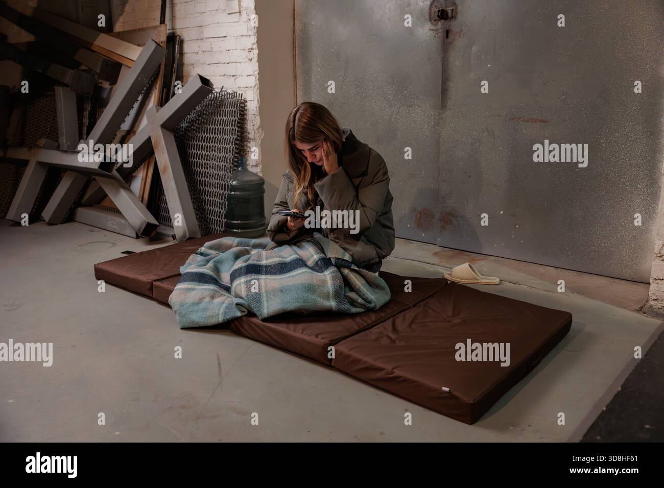 Donna che legge notizie al telefono nel rifugio antiatomico. Guerra in Ucraina. La vita in una stazione della metropolitana di un rifugio antiatomico. Donna che legge notizie sul cellulare Foto Stock