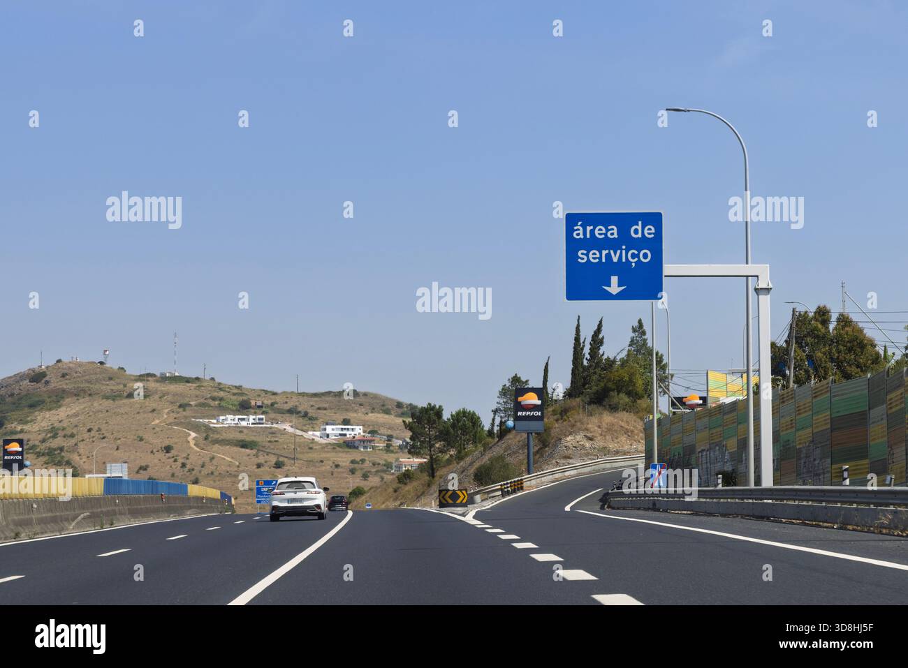 Cartello blu "Área de Servico" (area di servizio) su un'autostrada portoghese, che indica un'uscita imminente per servizi come il gas e il cibo. Annuncio Repsol. Foto Stock