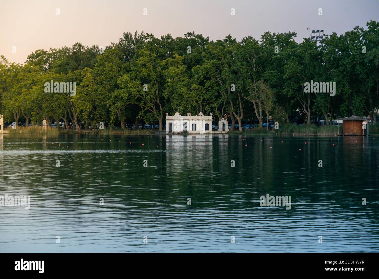 La storica Pesqueres de Banyoles (Case dei pescatori) costruita sull'acqua del lago Banyoles, che si riflette nelle acque calme al tramonto, in Spagna Foto Stock