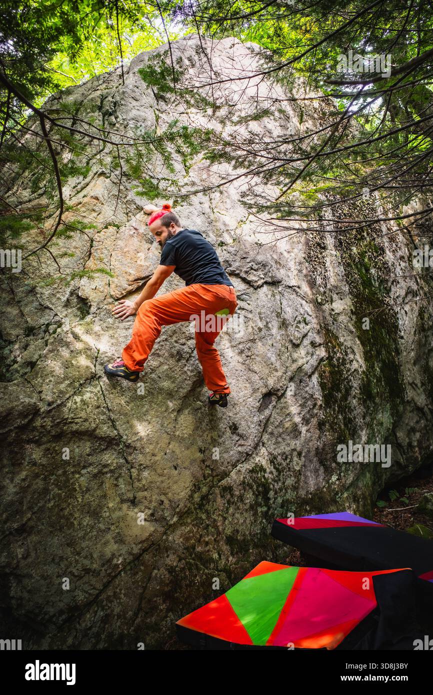 Un arrampicatore maschio in cerca di una presa per il piede su un problema di bouldering Foto Stock