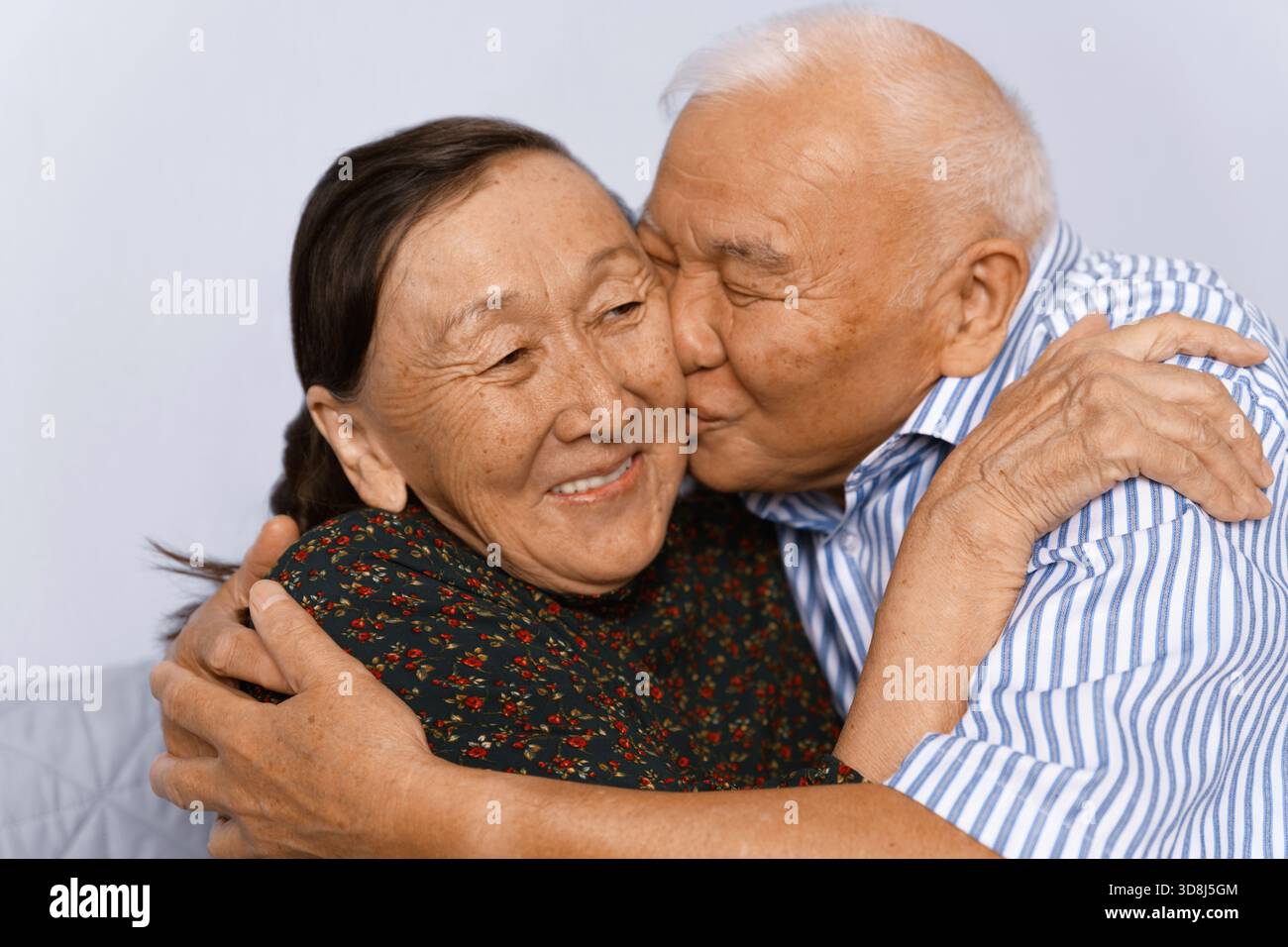 Uomo anziano che abbraccia e bacia sua moglie Foto Stock