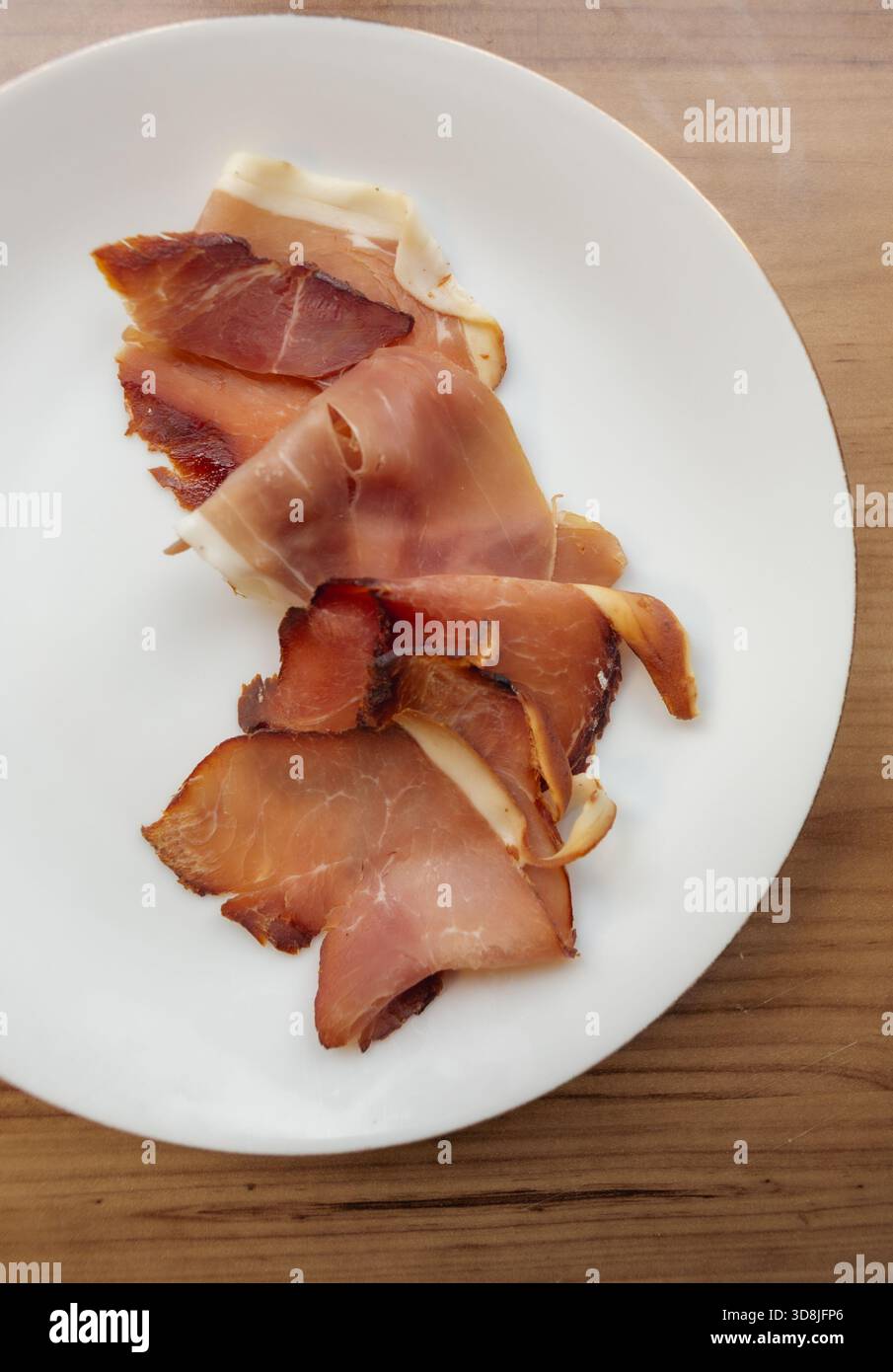 Affettare il prosciutto su un piatto bianco Foto Stock