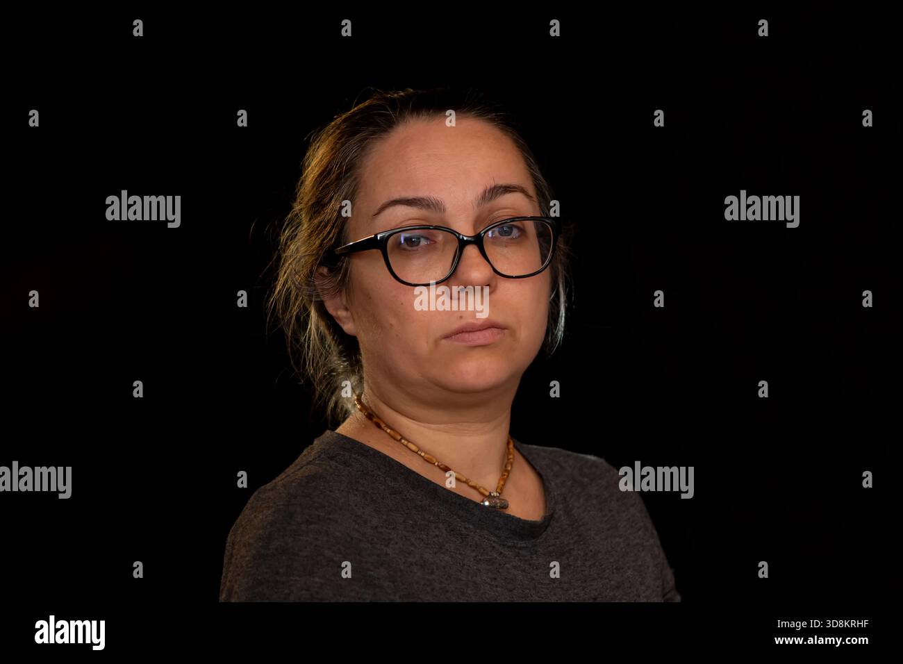 Ritratto in studio di una donna con occhiali su sfondo scuro Foto Stock