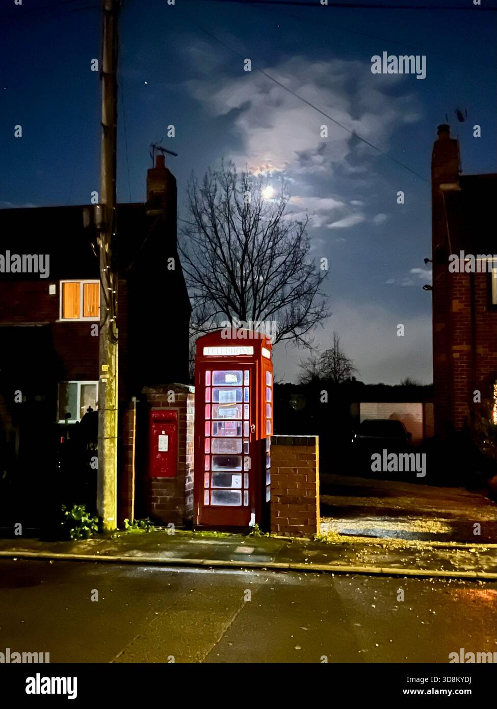 Una cabina telefonica rossa, di notte, ancora collegata e funzionante, a Criddling Stubbs, un piccolo villaggio a sud di Selby, North Yorkshire, Inghilterra settentrionale, Regno Unito - Immagine stock catturata con smartphone