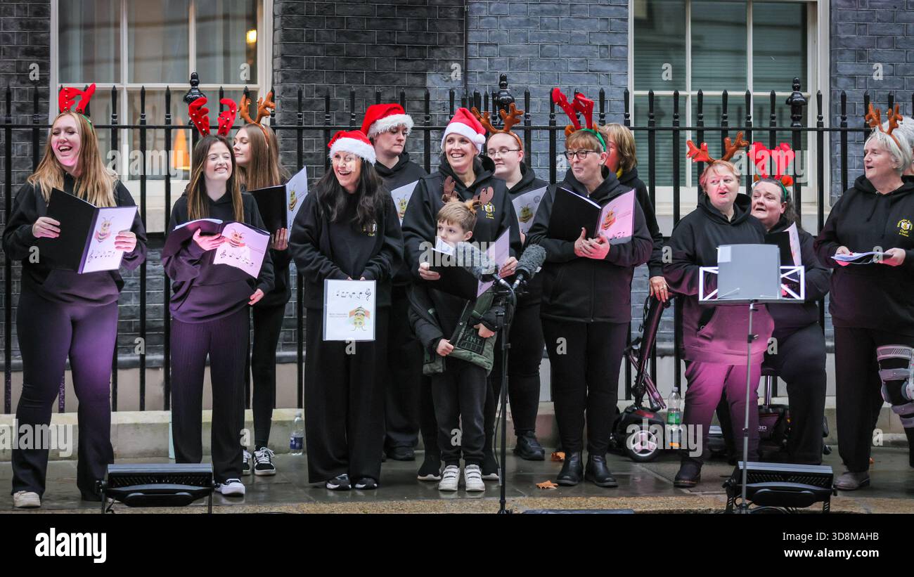 Londra, Regno Unito. 1 dicembre 2025. Il Manchester Survivors Choir canta canzoni. Sir Keir Starmer, primo ministro del Regno Unito, insieme a sua moglie Lady Victoria Starmer accende le luci dell'albero di Natale di Downing Street al 10. È aiutato dal quattordicenne volontario anti-letame Samuel Salamone, che preme il pulsante rosso. La cerimonia festiva è osservata da ospiti invitati e accompagnata da un coro e musica. Crediti: Imageplotter/Alamy Live News Foto Stock