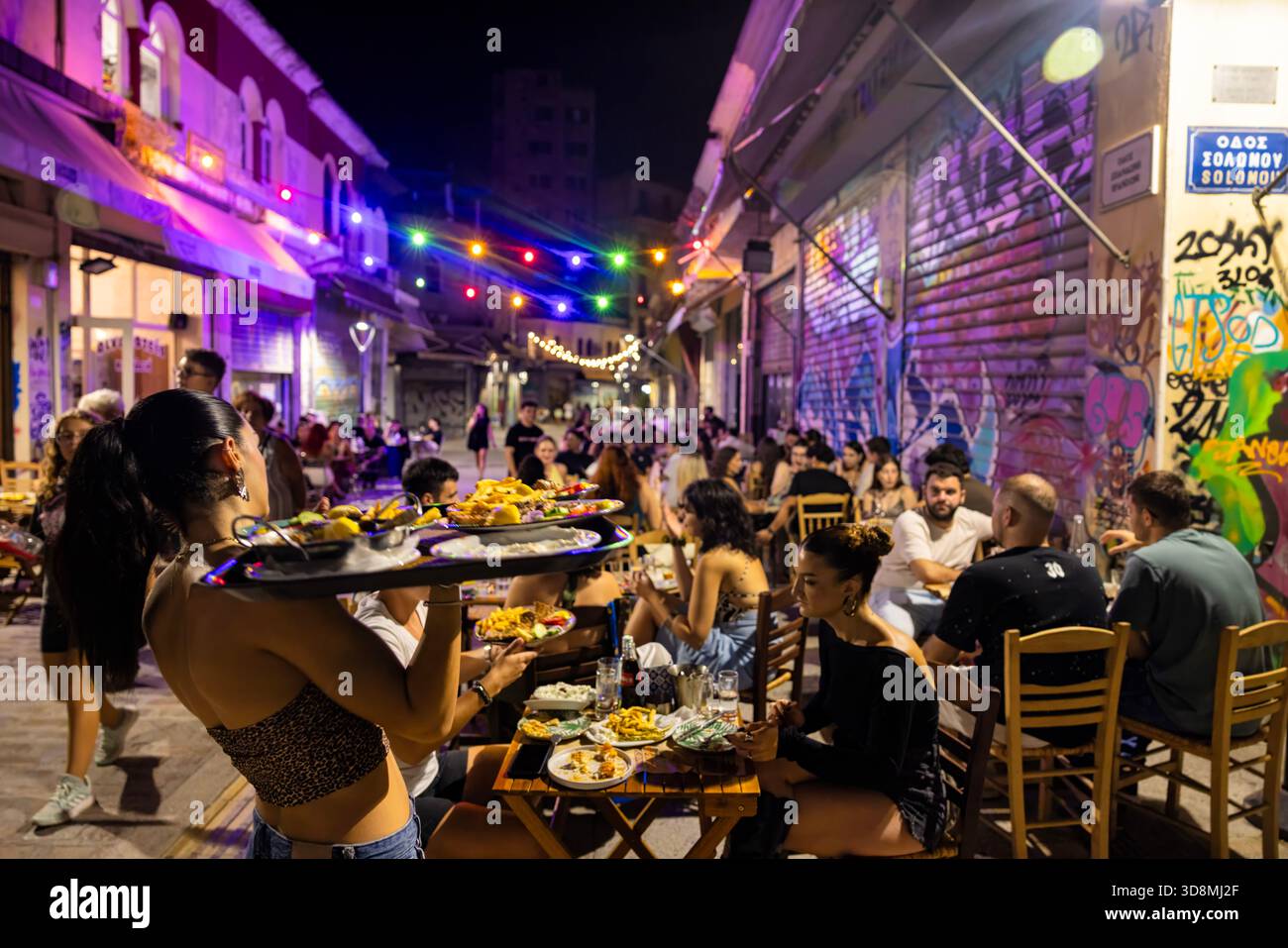 Salonicco, Grecia, 17 settembre 2025. Il mercato di Kapani si trasforma in un vivace centro di ristorazione con tavoli, cibo e persone sotto le luci festose. Foto Stock