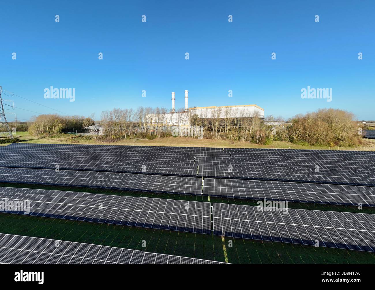 Vista aerea di file di pannelli solari che si estendono verso gli edifici industriali sotto il vasto cielo blu, Spalding, Inghilterra, Regno Unito. Foto Stock
