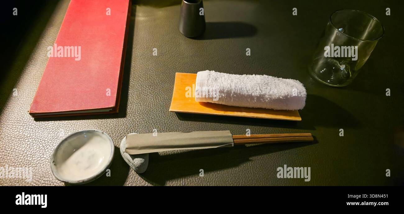 La disposizione da pranzo giapponese presenta bacchette, asciugamano e vetro su un tavolo con texture. Foto Stock