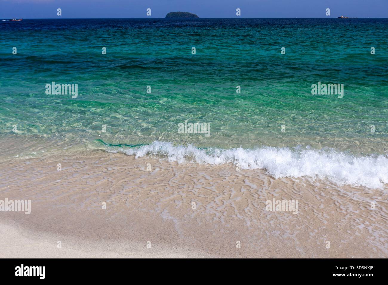 Mare cristallino color smeraldo che lambisce dolcemente su una spiaggia di sabbia incontaminata a Koh Adang, Thailandia. Foto Stock