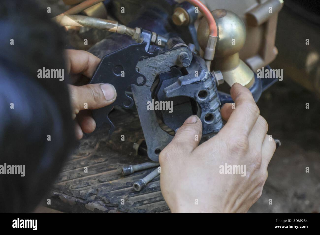 Primo piano della mano del meccanico che mostra la concentrazione durante gli interventi di riparazione su un componente del freno in metallo. la mano sporca simboleggia il lavoro manuale nell'assistenza tecnica w Foto Stock