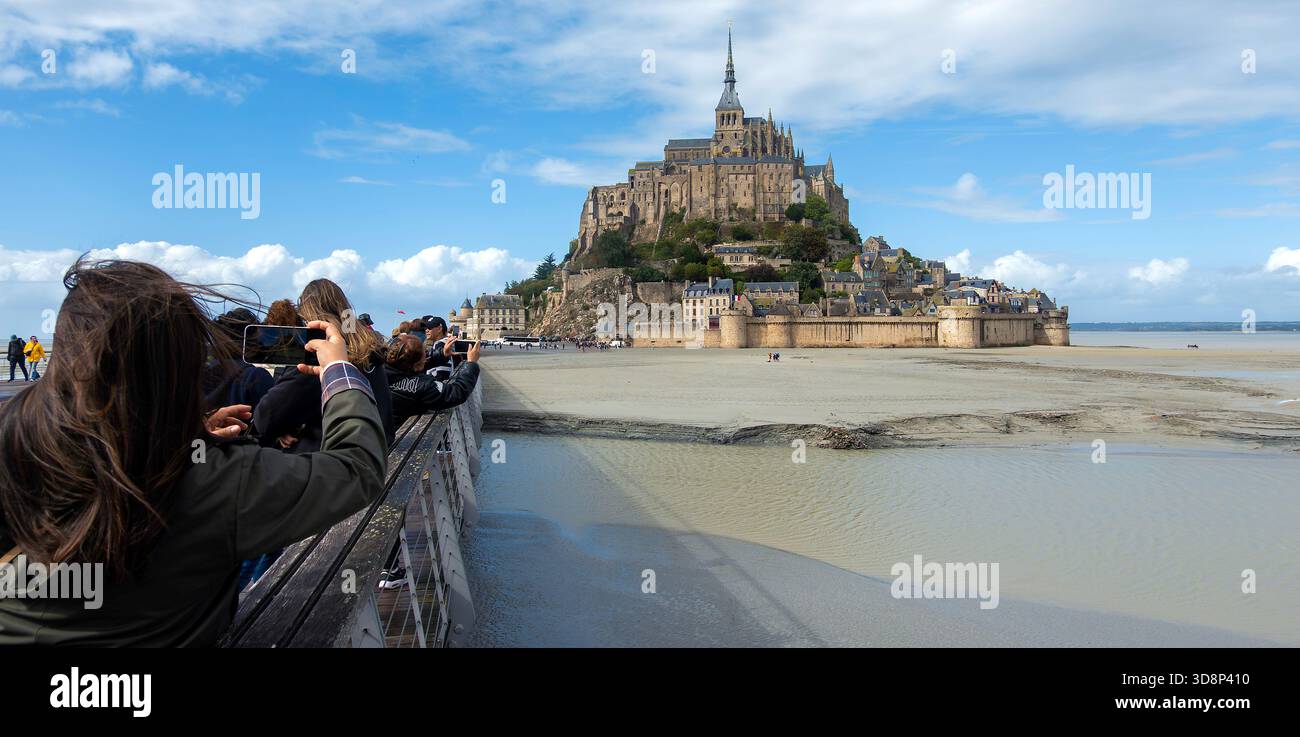 La gente fotografa Mont-Saint-Michel in Normandia, Francia, dalla strada rialzata in bassa marea Foto Stock