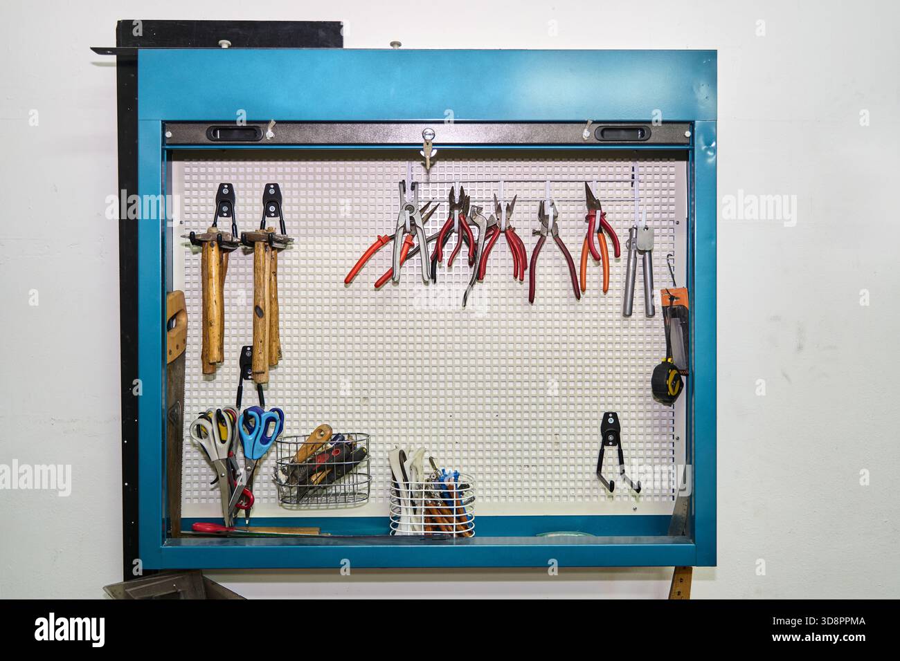Armadietto per conservazione a parete in Pegboard in un'officina professionale, per immagazzinare martelli, pinze e altri utensili per la lavorazione e la riparazione Foto Stock