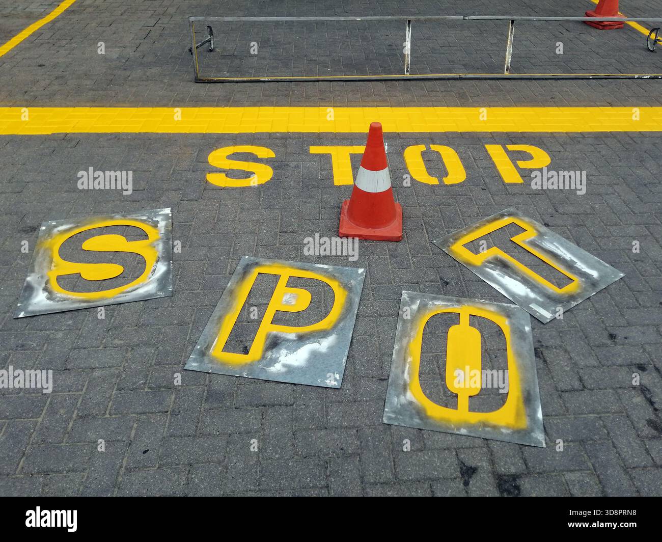 Segnale DI STOP appena verniciato su asfalto, messa a fuoco selettiva. Segnaletica stradale in corso con stencil e coni Foto Stock