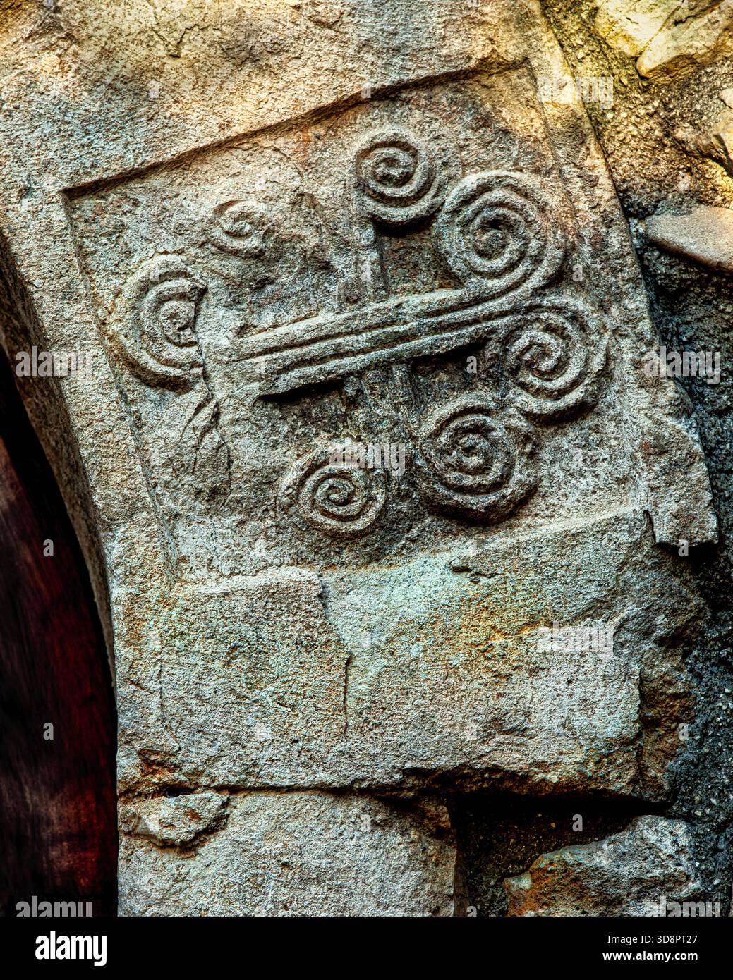 Il bassorilievo in pietra raffigura un motivo decorativo lombardo; il motivo centrale combina una croce con elementi a spirale. Abruzzo, Italia, Europa Foto Stock