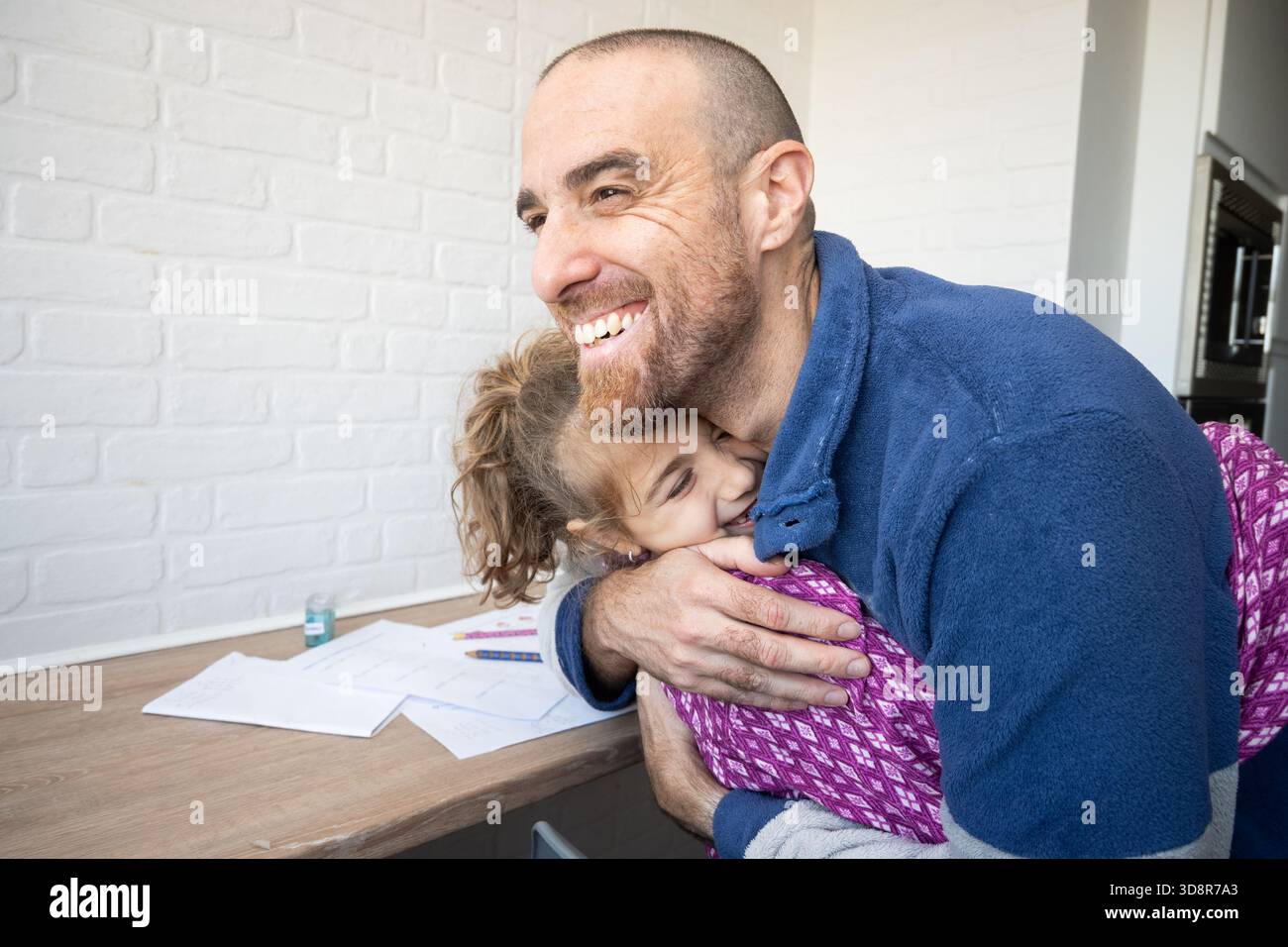Padre abbraccia sua figlia dopo aver finito i compiti a scuola Foto Stock
