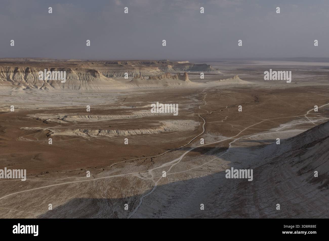 Remoto altopiano desertico di Ustyurt caratterizzato da formazioni rocciose bianche, scogliere erose e tortuose strade sterrate che si estendono attraverso un vasto e incontaminato geologico Foto Stock