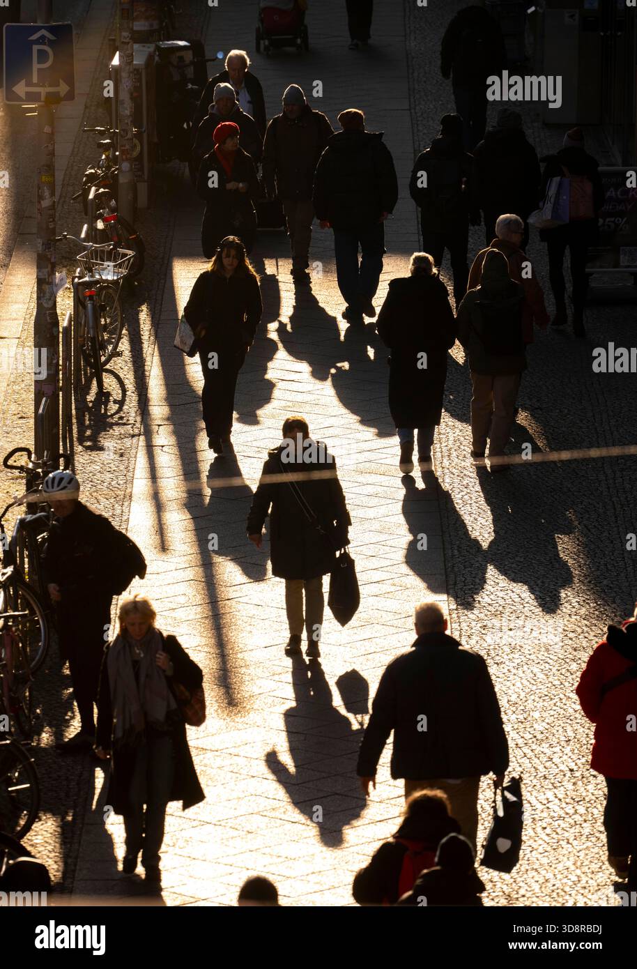 Passanti su un marciapiede su Friedrichstraße a Berlino, ombre, sole basso, inverno, Germania Foto Stock