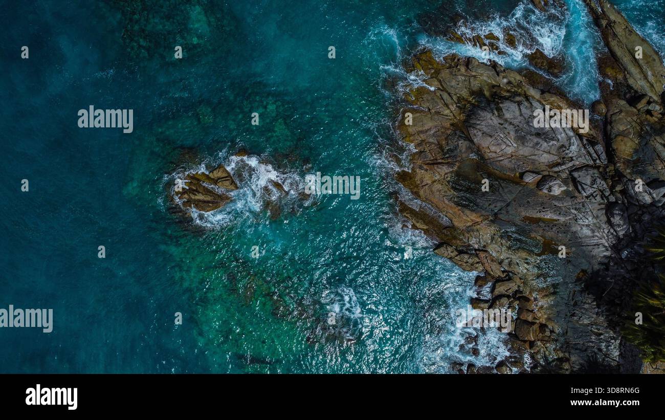 Wave Power: Schiuma bianca che ruota intorno al Dark Rocky Headland Foto Stock