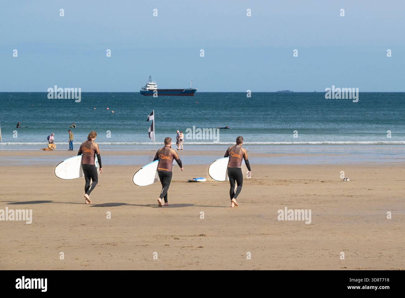 Tre vacanzieri in una lezione di surf con la Cornish Wave Surf School presso Towan Beach a Newquay, in Cornovaglia, in Inghilterra, nel Regno Unito. Foto Stock
