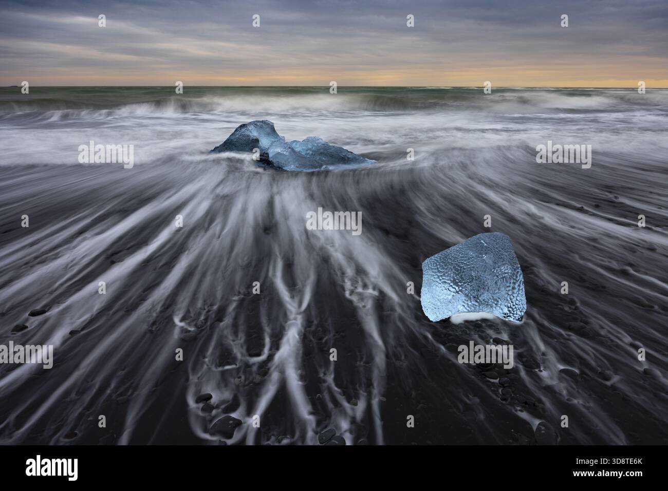 Vista dei luminosi diamanti di ghiaccio sparsi attraverso la spiaggia di sabbia nera mentre la marea scorre sotto un cielo crepuscolo, Diamond Beach, Sveitarfelag Foto Stock