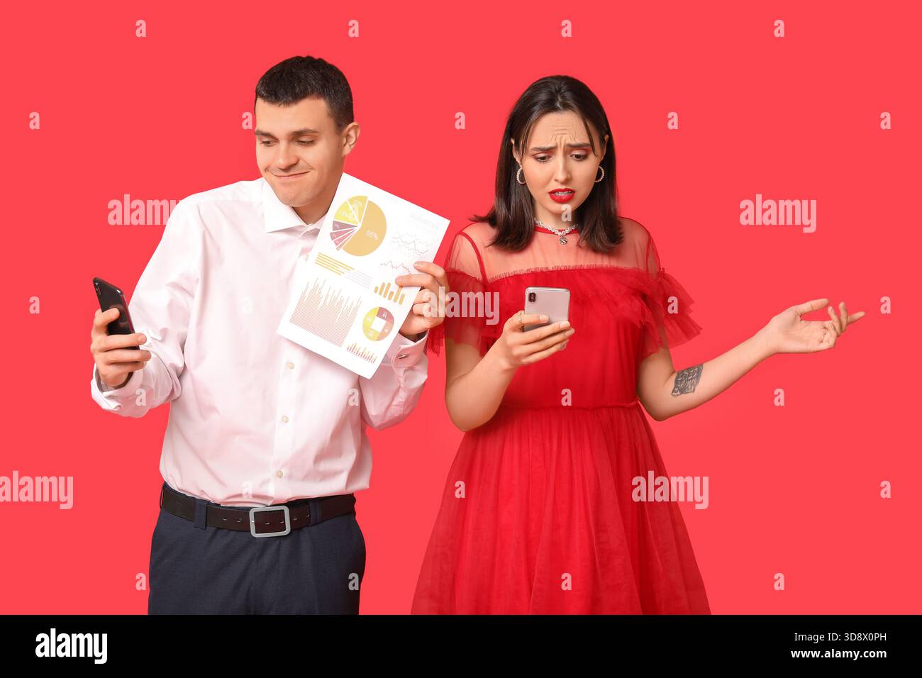 Giovane coppia che tiene in mano telefoni cellulari e carta con carte su sfondo rosso. Incontri online Foto Stock