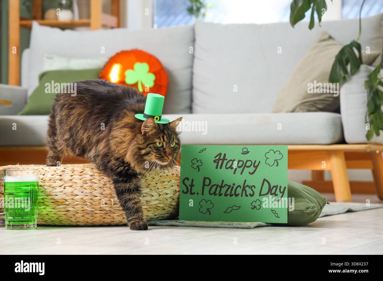 Simpatico gatto con cappello da leprechaun con tazza di birra verde e cartolina festiva per la festa di San Patrizio a casa Foto Stock