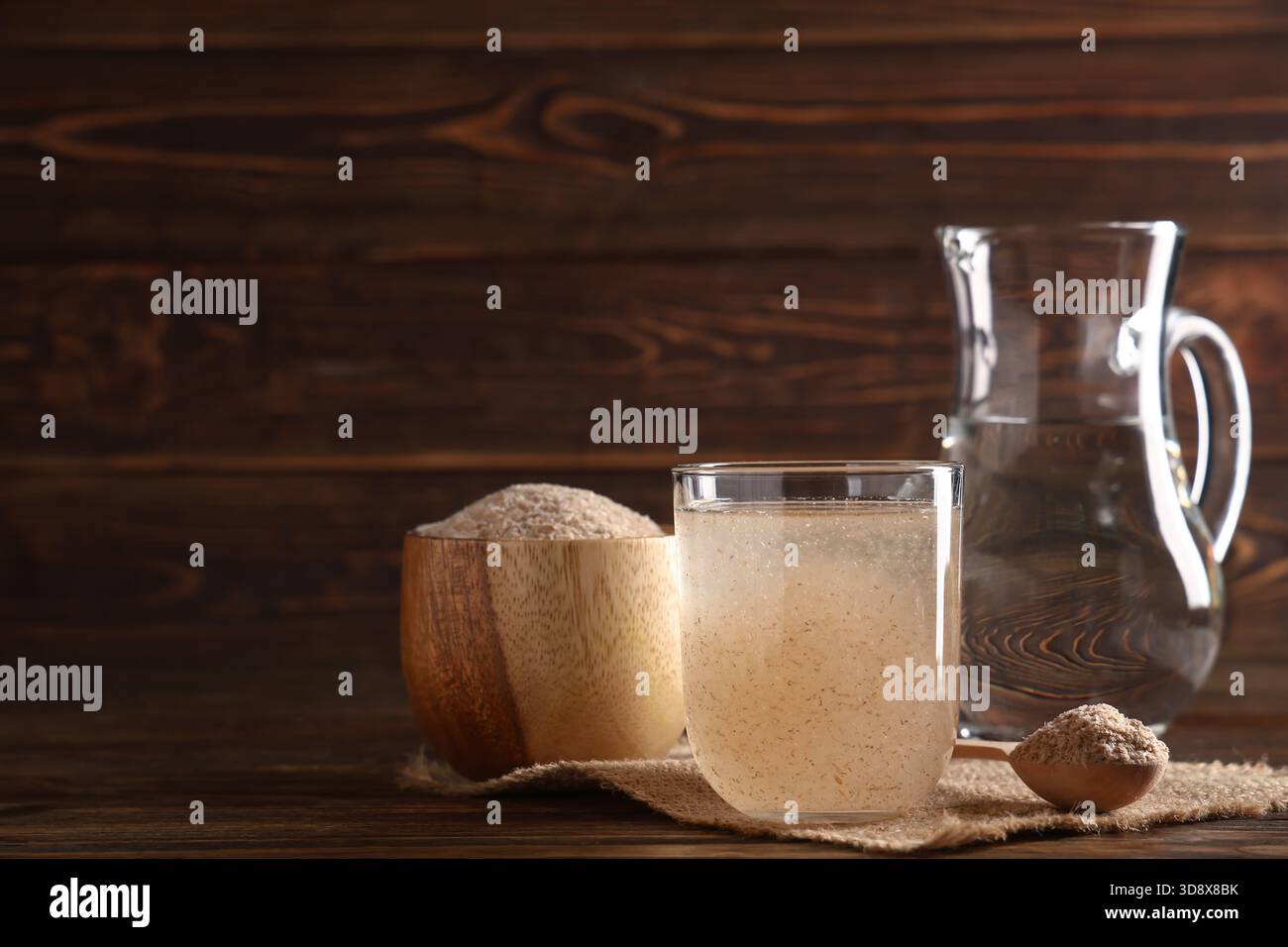 Bicchiere d'acqua con buccia di psico su fondo di legno Foto Stock