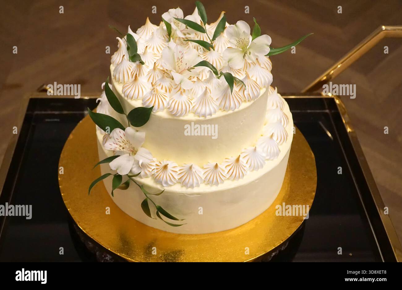 Torta nuziale, una torta panna decorata con panna e fiori su un vassoio dorato Foto Stock