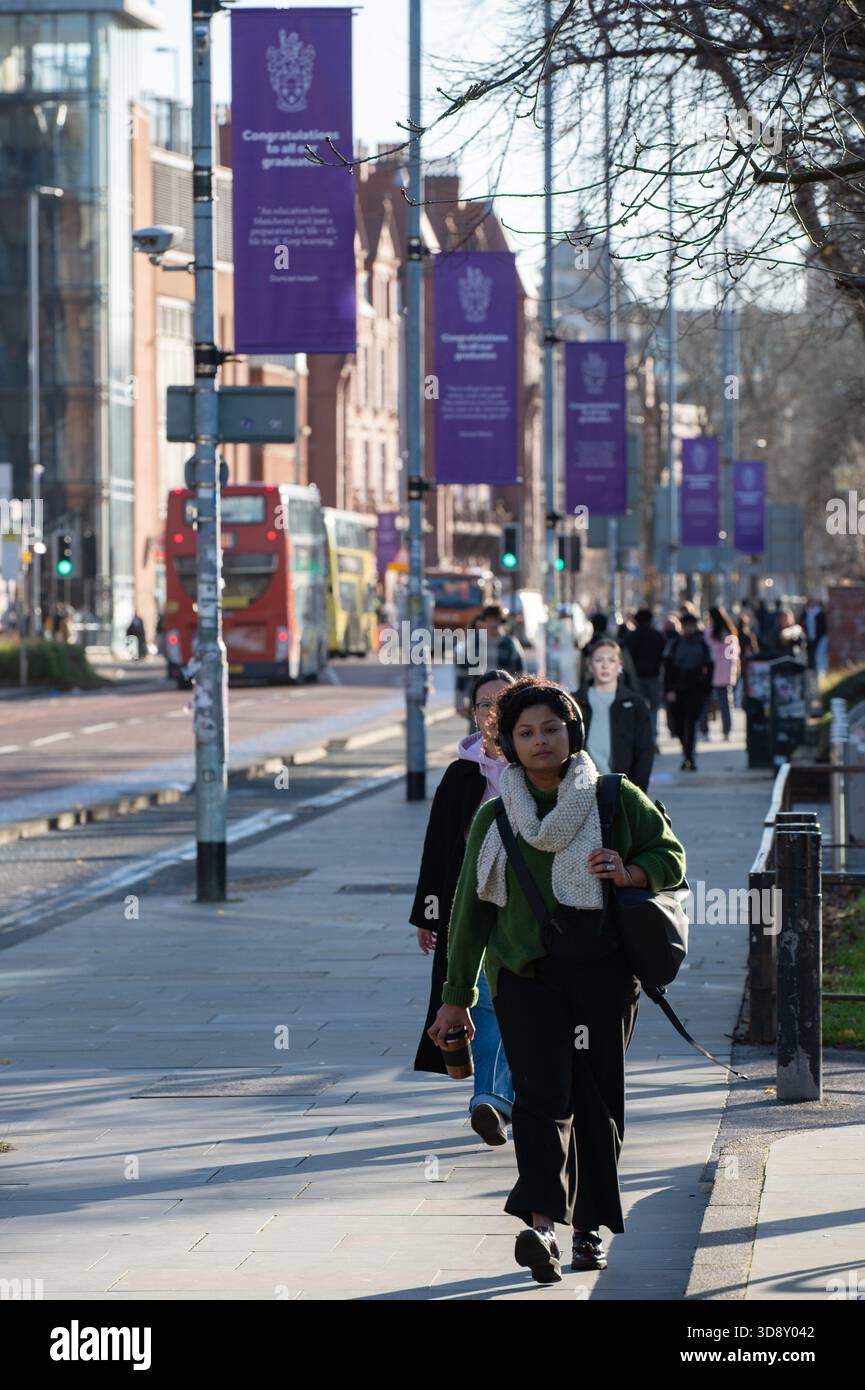 Gli studenti si dirigono lungo Oxford Road, una strada trafficata dell'Università di Manchester. Foto Stock