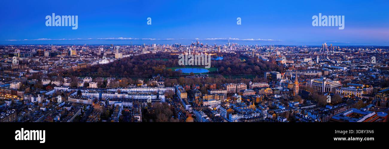 Splendida antenna al crepuscolo di Hyde Park a Londra e dell'elegante quartiere di Kensington, con luci calde che illuminano le case storiche e le strade alberate Foto Stock