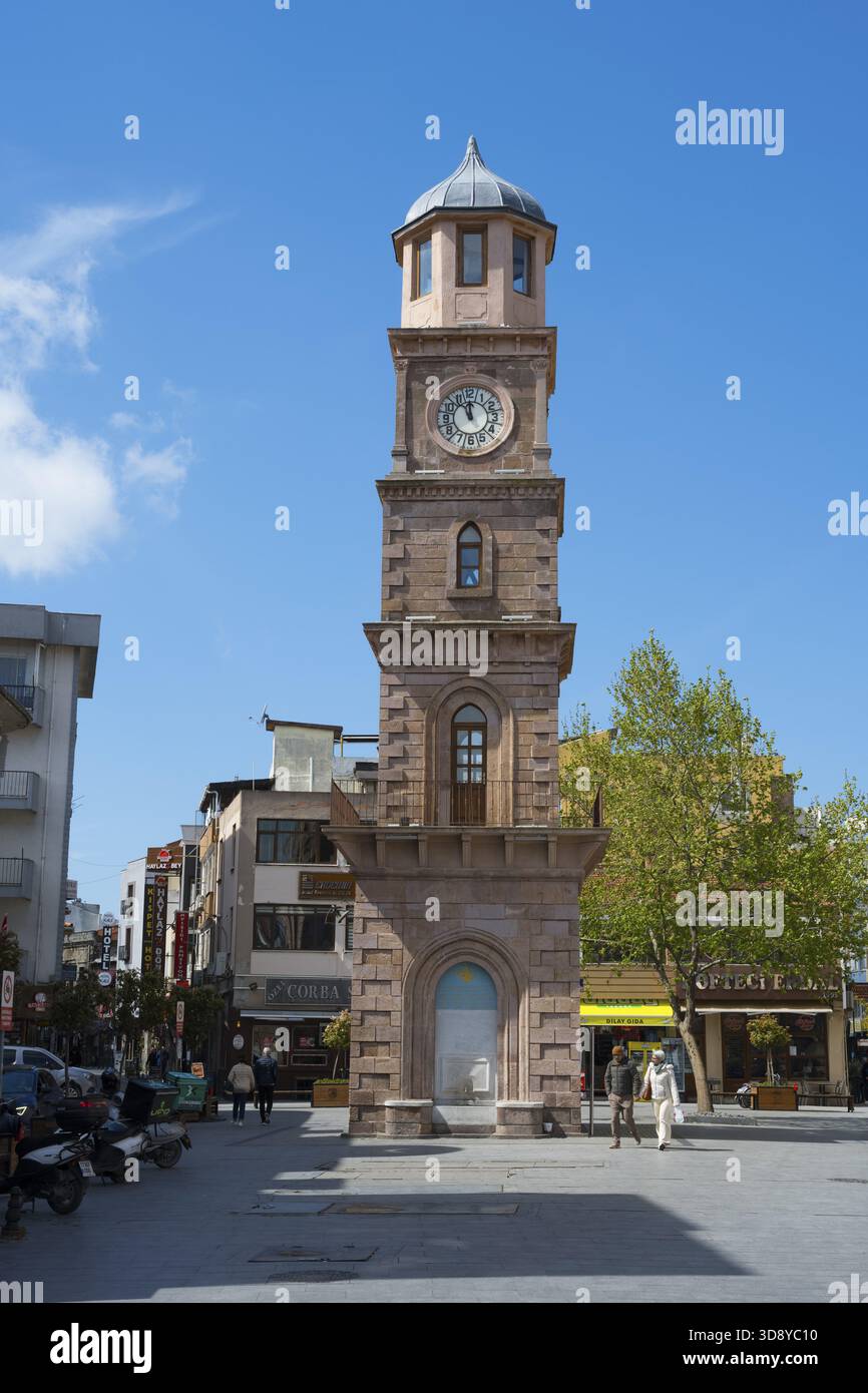 Un'alta torre dell'orologio in una piazza urbana con alberi e negozi, Canakkale Clock Tower, Canakkale, regione di Marmara, Turchia Foto Stock