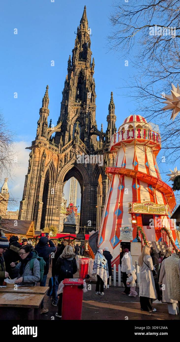 Il monumento Scott domina Princes Street in un fresco giorno invernale, incorniciato dal trambusto festoso dei mercatini di Natale di Edimburgo Foto Stock