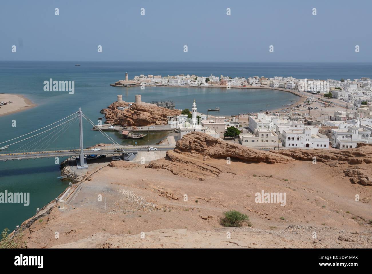 Città costiera di Sur in Oman con ponte sospeso, edifici bianchi e penisola rocciosa Foto Stock