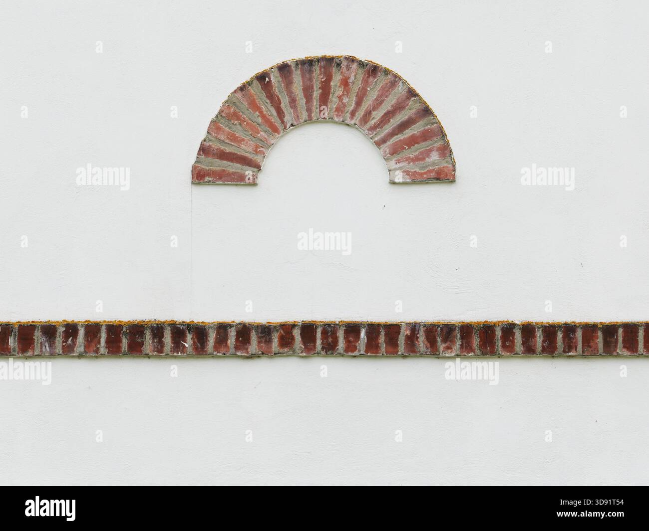 Arco rotondo utilizzato come elemento decorativo ad arco cieco in una parete intonacata con ornamenti in mattoni. Foto Stock