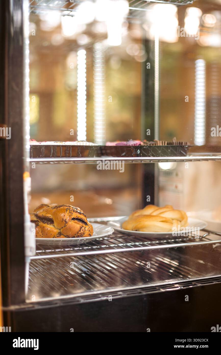 Primo piano di pasticcini assortiti al forno dietro una vetrina in vetro: Croissant freschi, danesi e panini dolci. Perfetto per prodotti da forno, cibo, stile di vita Foto Stock